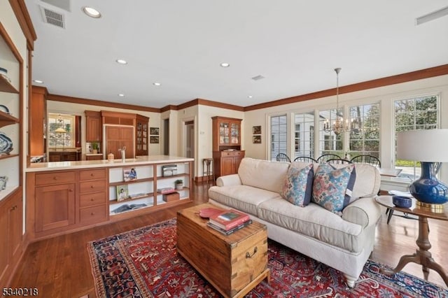 living area with recessed lighting, a notable chandelier, visible vents, ornamental molding, and dark wood-style floors