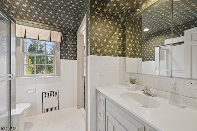 bathroom with wainscoting, radiator, toilet, vanity, and tile walls