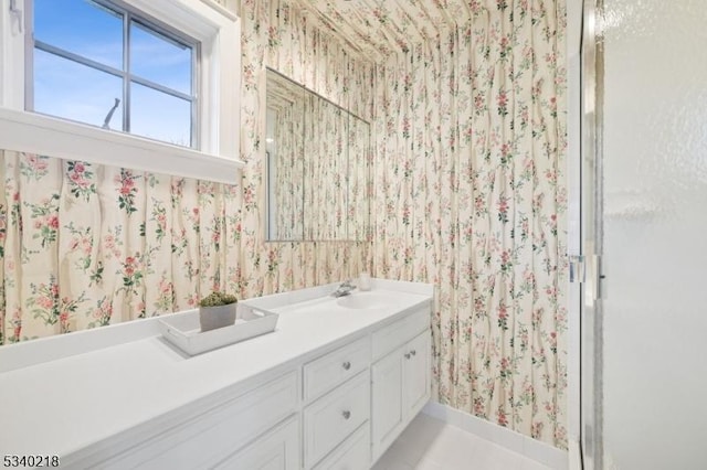 bathroom featuring a shower with door, vanity, and wallpapered walls