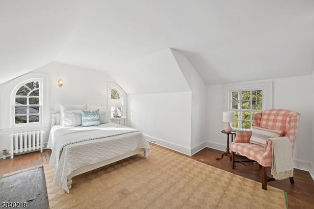 bedroom with light wood-type flooring, radiator heating unit, baseboards, and lofted ceiling