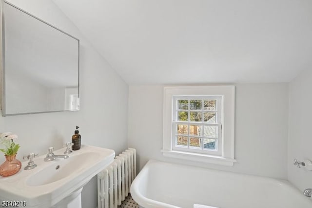 full bathroom featuring lofted ceiling, radiator heating unit, a bathtub, and a sink