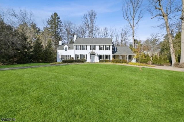 view of front of house with a chimney and a front lawn