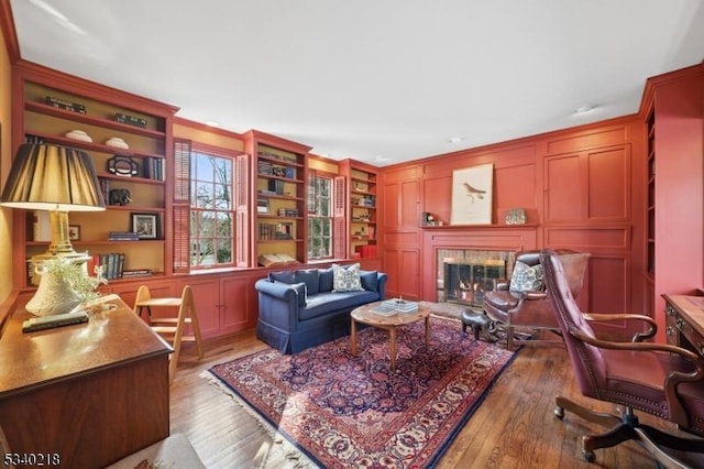 interior space featuring crown molding, dark wood-type flooring, a glass covered fireplace, and a decorative wall