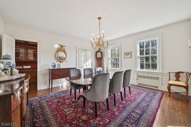 dining space featuring ornamental molding, radiator, dark wood-style flooring, and an inviting chandelier