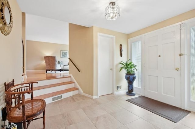 foyer featuring visible vents, stairway, baseboards, and light tile patterned floors