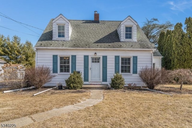 cape cod house with a shingled roof, a chimney, and a front lawn