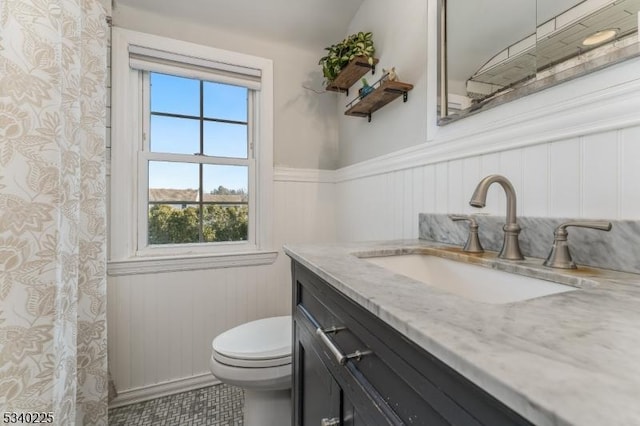 full bath featuring a wainscoted wall, vanity, and toilet