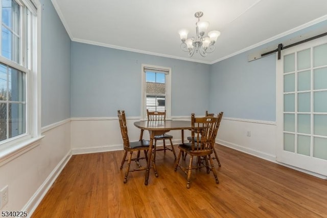 dining area with wood finished floors, crown molding, baseboards, and a barn door