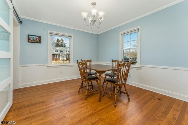 dining room with crown molding, wood finished floors, a wealth of natural light, and a notable chandelier