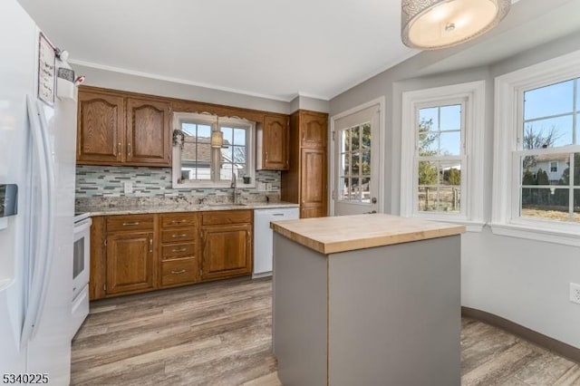 kitchen featuring white appliances, light wood-type flooring, backsplash, and brown cabinets