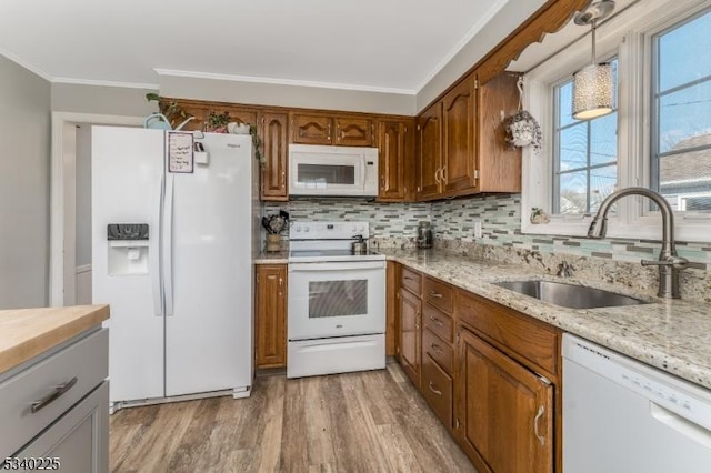 kitchen with white appliances, a sink, crown molding, light wood-type flooring, and backsplash