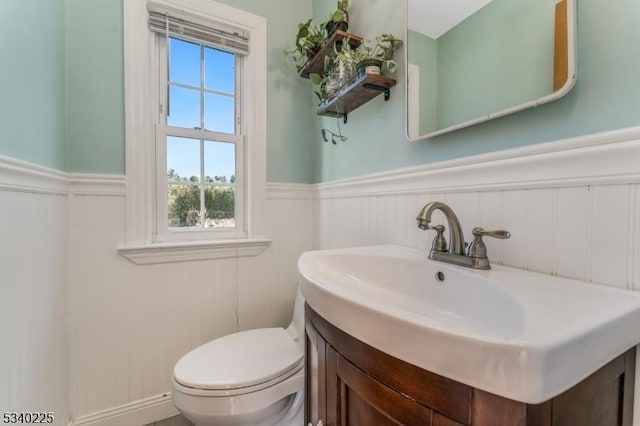 bathroom with a wainscoted wall, vanity, and toilet