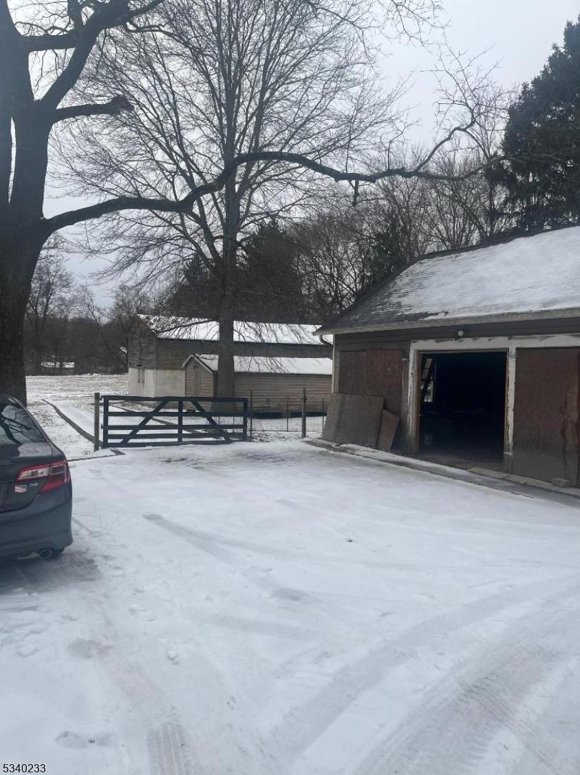 snow covered property featuring an outdoor structure and fence