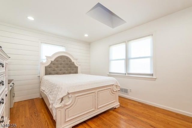 bedroom with light wood-style floors, visible vents, baseboards, and multiple windows