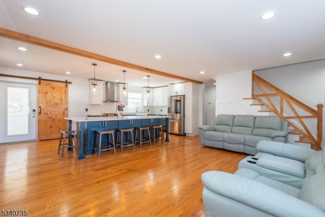 living room with light wood finished floors, a barn door, stairs, and recessed lighting