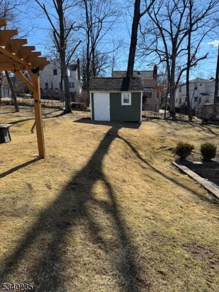 view of yard featuring a residential view, an outdoor structure, a storage shed, and a pergola