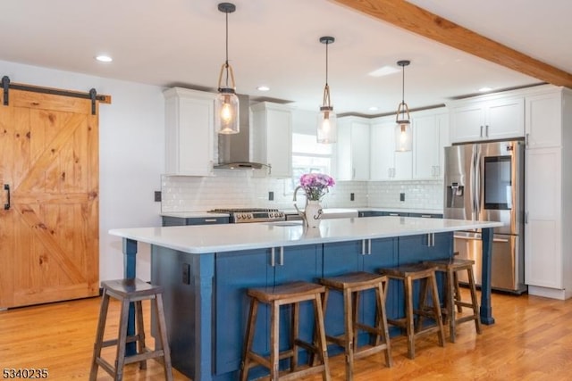 kitchen featuring a barn door, white cabinets, light countertops, wall chimney range hood, and stainless steel refrigerator with ice dispenser