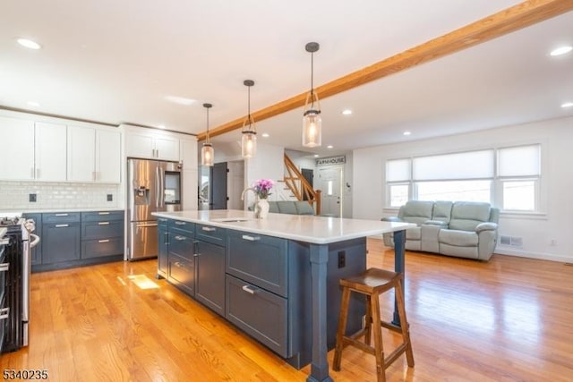 kitchen with light wood finished floors, light countertops, decorative backsplash, appliances with stainless steel finishes, and white cabinetry