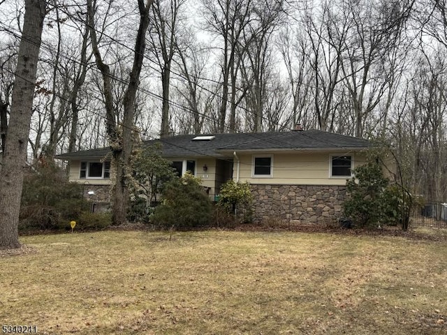 single story home featuring stone siding, a chimney, and a front yard