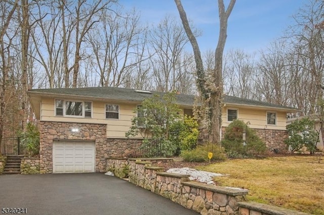 view of front of house with a garage, stone siding, and driveway