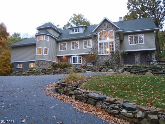 shingle-style home featuring stone siding and a chimney