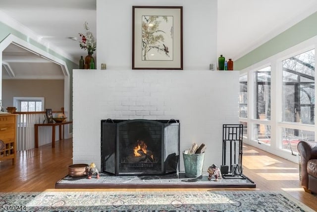 interior details featuring a brick fireplace, arched walkways, wood finished floors, and ornamental molding