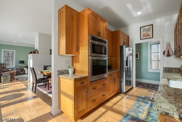 kitchen featuring stainless steel appliances, light wood-type flooring, and brown cabinetry