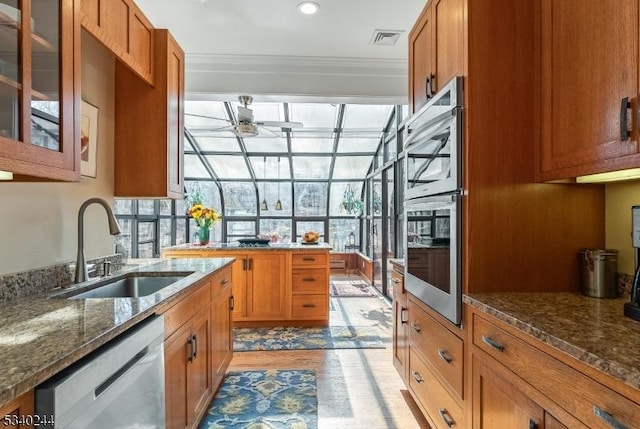 kitchen featuring appliances with stainless steel finishes, brown cabinetry, visible vents, and a sink