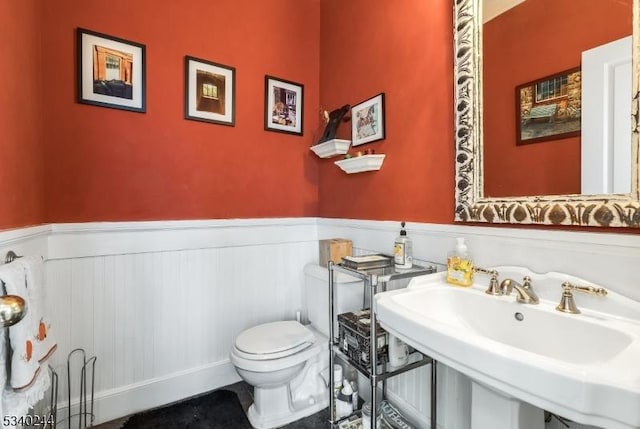 bathroom with a wainscoted wall, a sink, and toilet