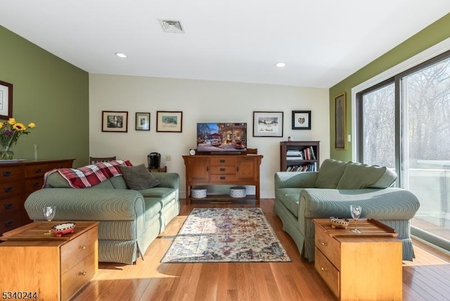 living area with recessed lighting, visible vents, and light wood finished floors