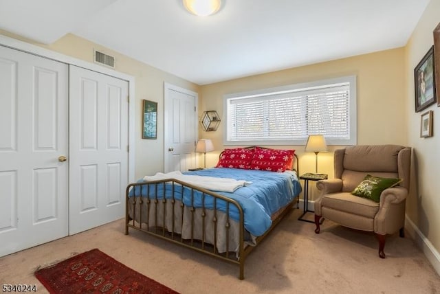 carpeted bedroom with visible vents and multiple closets