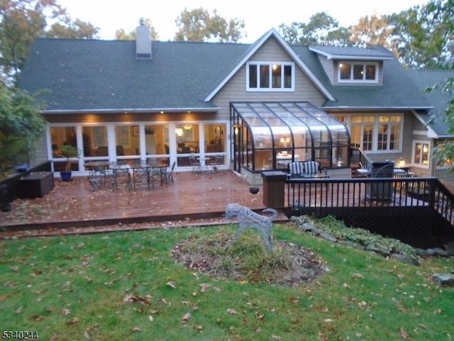 back of property featuring a sunroom, a lawn, and a deck