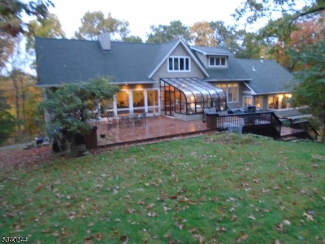 rear view of house with a sunroom, a yard, and a deck