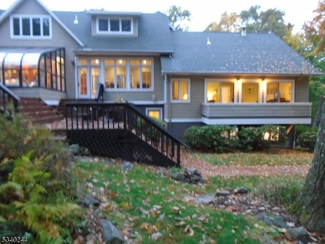 back of property with a sunroom, stairway, and a wooden deck