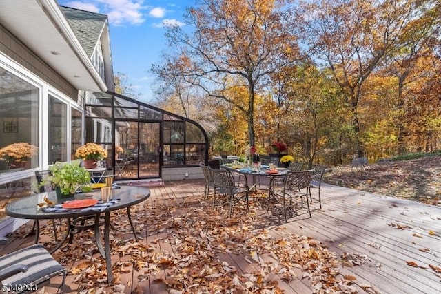 wooden deck with outdoor dining area and glass enclosure