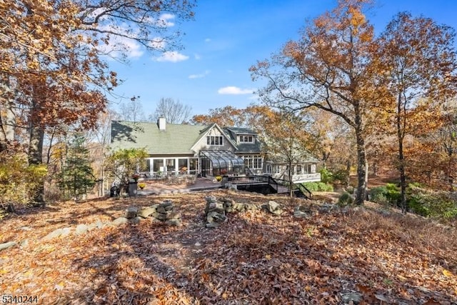 back of house with a sunroom and a chimney