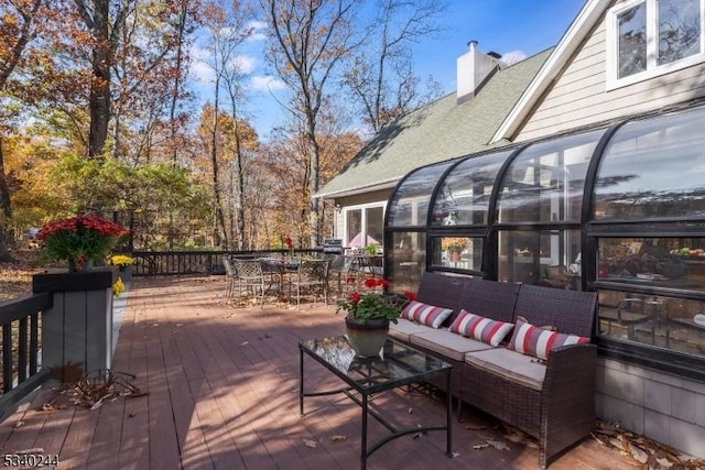 wooden terrace featuring outdoor dining space, outdoor lounge area, and a sunroom