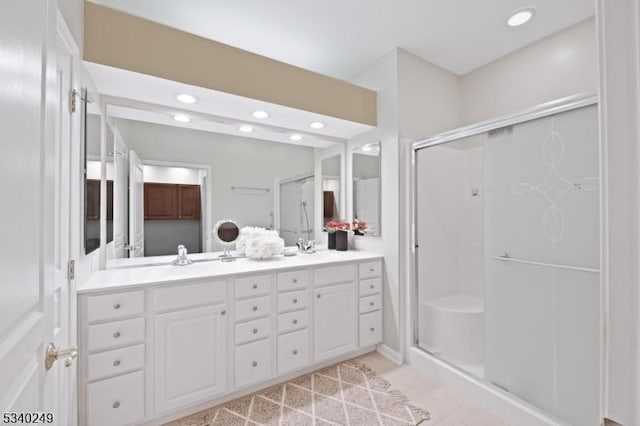 bathroom featuring double vanity, a shower stall, a sink, and recessed lighting