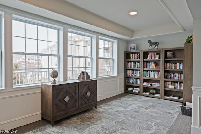 living area with wainscoting, light colored carpet, a wealth of natural light, and a decorative wall