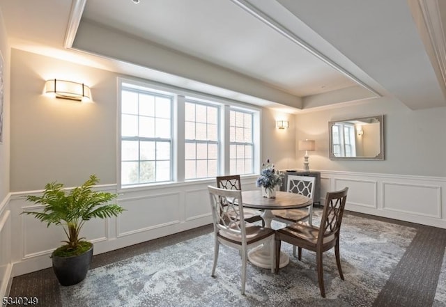 dining area with a wainscoted wall, a tray ceiling, and a decorative wall