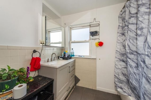 bathroom with curtained shower, tile patterned flooring, vanity, tile walls, and wainscoting