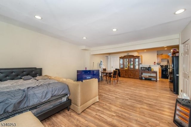 bedroom with light wood finished floors, freestanding refrigerator, and recessed lighting