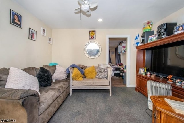 living room featuring a ceiling fan, dark colored carpet, and radiator heating unit