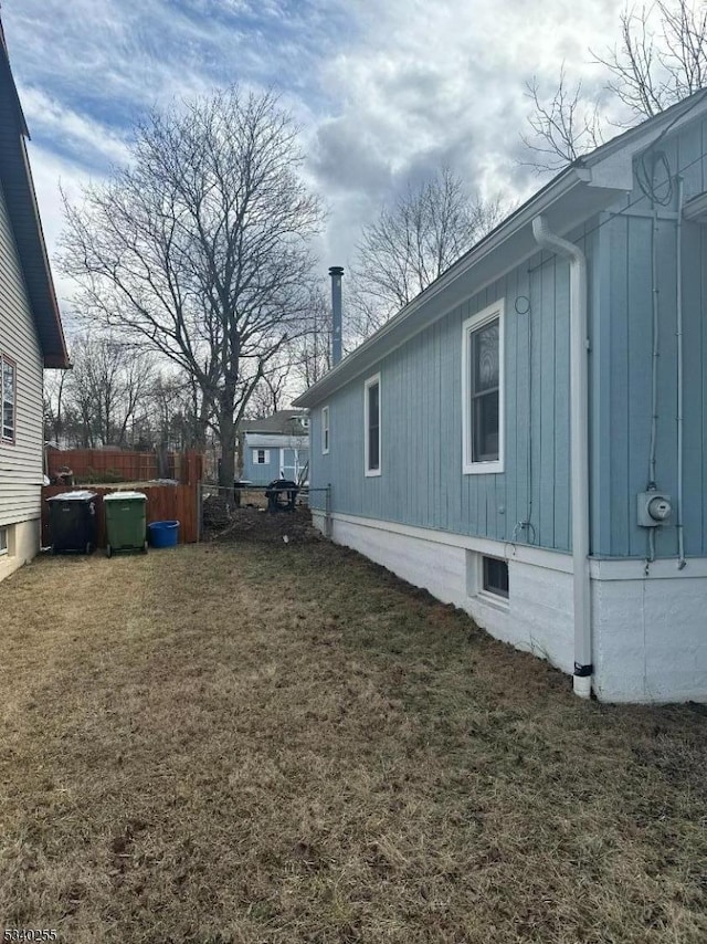 view of home's exterior featuring a lawn and fence