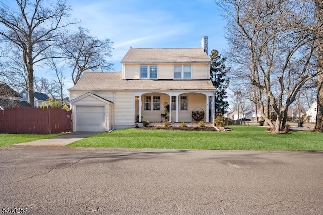 traditional-style home featuring a front yard, fence, driveway, a chimney, and a garage