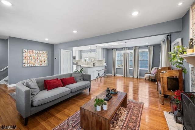 living area featuring recessed lighting, a fireplace, light wood-type flooring, and baseboards