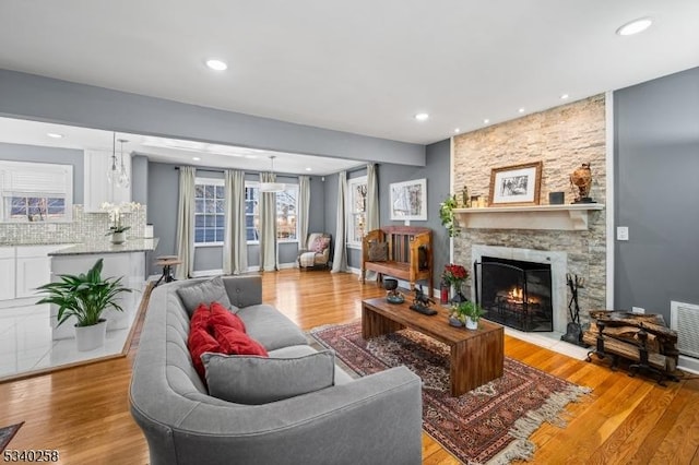 living area featuring recessed lighting, a fireplace, and light wood finished floors