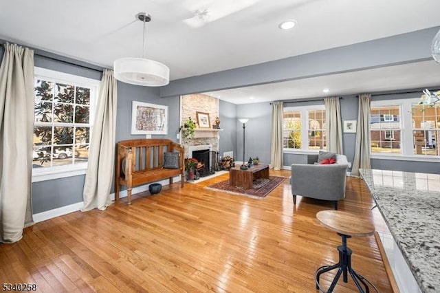 living room with recessed lighting, a fireplace, baseboards, and light wood finished floors