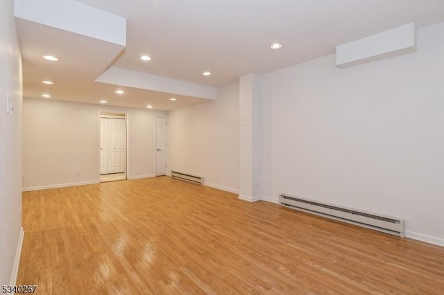 spare room featuring a baseboard heating unit, baseboards, light wood-style flooring, and recessed lighting