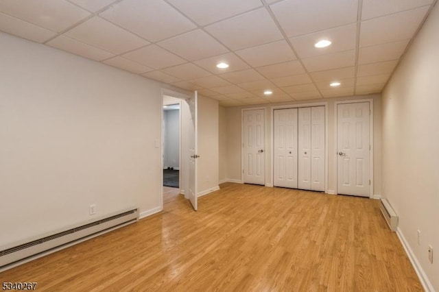 unfurnished bedroom featuring light wood-type flooring, a baseboard radiator, and baseboards